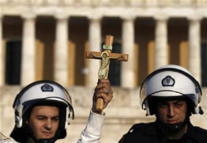 A protester holds a crucifix in front of a riot policemen during a rally at Athens' Syntagma square, March 27, 2011.