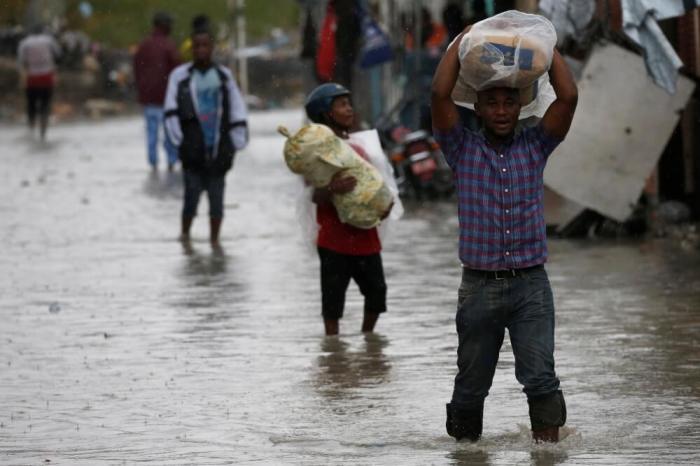 People carry their belongings as they wade across a flooded street while Hurricane Matthew passes through Port-au-Prince, Haiti, October 4, 2016.