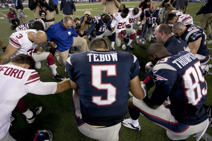 New England Patriots quarterback Tim Tebow prays with his teammates and members of the New York Giants after their NFL preseason game in Foxborough, Massachusetts, August 29, 2013.