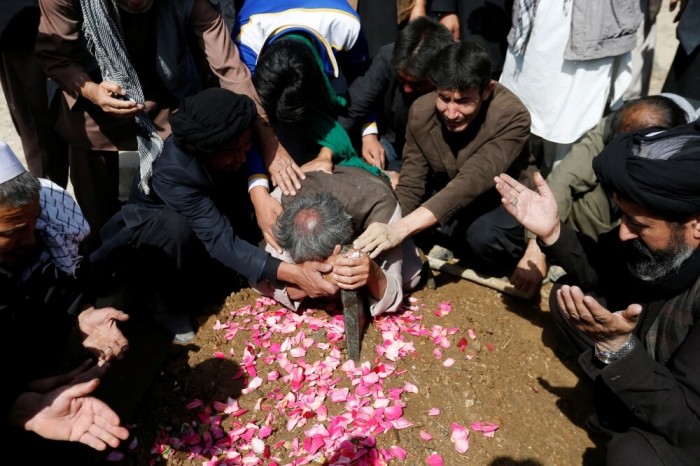 Afghan Shi'ite Muslims men mourn over the grave of a victim who was killed in Tuesday's attack at the Sakhi Shrine in Kabul, Afghanistan, October 12, 2016.