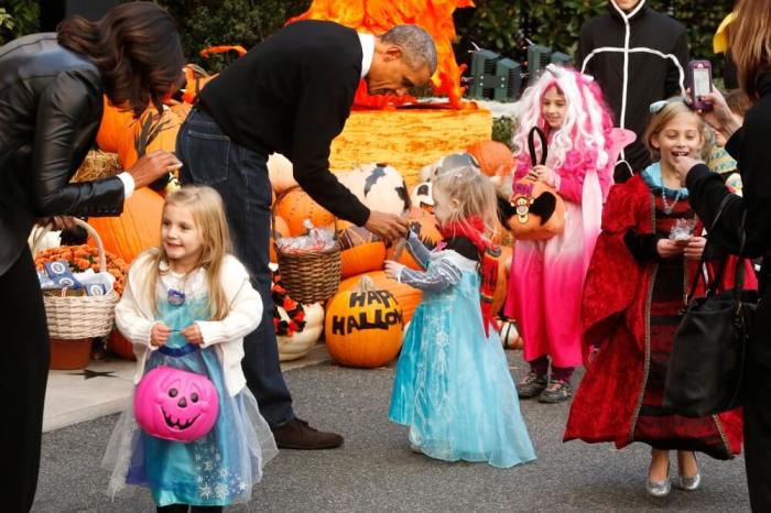 U.S. President Barack Obama (2nd L) and first lady Michelle Obama (L) receive children on the South Lawn for a Halloween trick-or-treating celebration in Washington October 31, 2014. Invitees included local children and the children of military families, according to the White House.