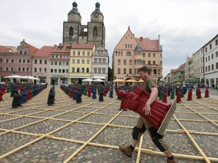 An assistant carries a plastic statuette of 16th-century Protestant reformer Martin Luther, which is part of the art installation 'Martin Luther - I'm standing here' by German artist Ottmar Hoerl, in the main square in Wittenberg, eastern Germany August 11, 2010.