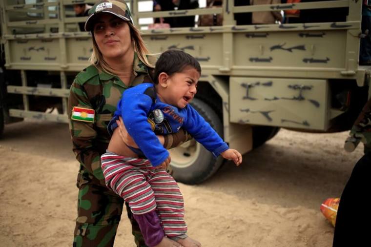 A Kurdish female Peshmerga soldier carries a newly internally displaced boy as he cries upon his arrival at Al Khazar camp near Hassan Sham, east of Mosul, October 25, 2016.