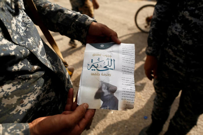 An Iraqi soldier shows a pamphlet which reads 'Wearing beards is compulsory, shaving is prohibited' along a street of the town of al-Shura, which was recaptured from Islamic State (IS) on Saturday, south of Mosul, Iraq October 30, 2016.