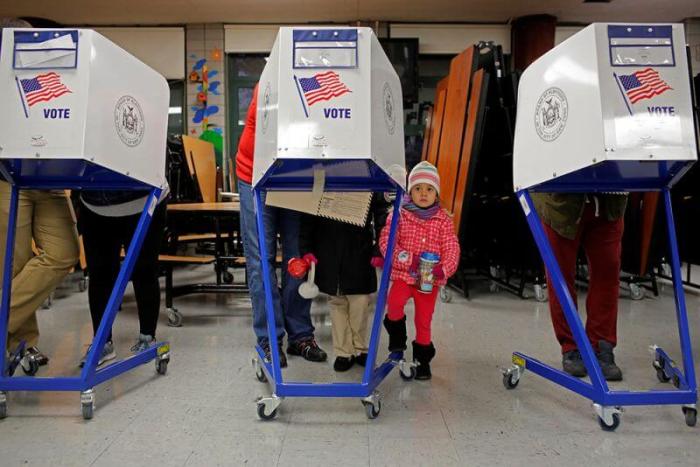 Myla Gibson, 3, waits as her father Ken Gibson fills out a ballot for the U.S presidential election at the James Weldon Johnson school in the East Harlem neighborhood of Manhattan, New York City, November 8, 2016.