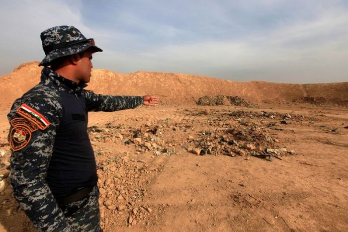 A member of Iraqi security forces gestures towards a mass grave for corpses in the town of Hammam al-Alil which was seized from Islamic State last week, Iraq November 9, 2016.