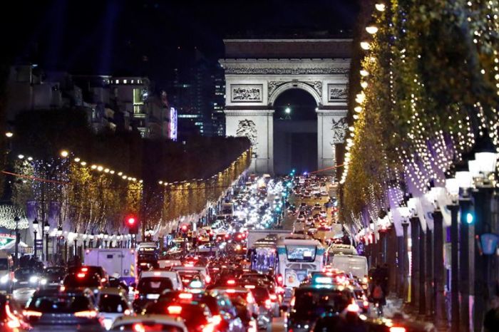 Christmas holiday lights hang from trees to illuminate the Champs Elysees avenue in Paris as rush hour traffic fills the avenue leading up to the Arc de Triomphe, France, November 21, 2016.