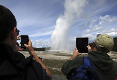 People use phones and tablets to photograph Old Faithful geyser erupting in Yellowstone National Park in Wyoming, May 16, 2014. The nearly 3,500 square mile park straddling the states of Wyoming, Montana and Idaho was founded in 1872 as America's first national park.
