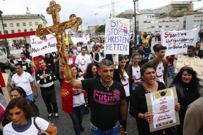 People hold crosses and signs during a rally organized by Iraqi Christians living in Germany denouncing what they say is repression by the Islamic State militant group against Christians living in Iraq, in Berlin, Aug. 17, 2014.