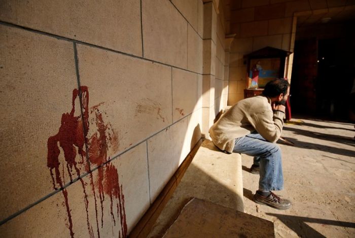An Egyptian Christian sits on a bench near a blood stain on a wall at the scene following a bombing inside Cairo's Coptic cathedral in Egypt December 11, 2016.