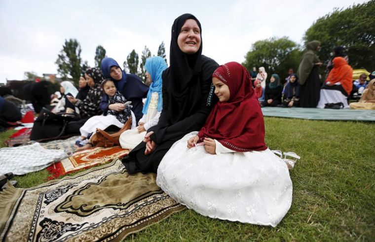 Muslim women and girls sit on prayer rugs before performing prayers for Eid-al Fitr to mark the end of the holy fasting month of Ramadan at a park in London, Britain, July 17, 2015.