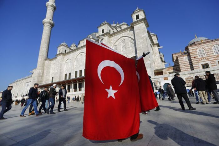 A street wendor sells Turkish flags in front of Fatih Mosque before funeral of police officers killed in Saturday's blasts in Istanbul, Turkey, December 11, 2016.