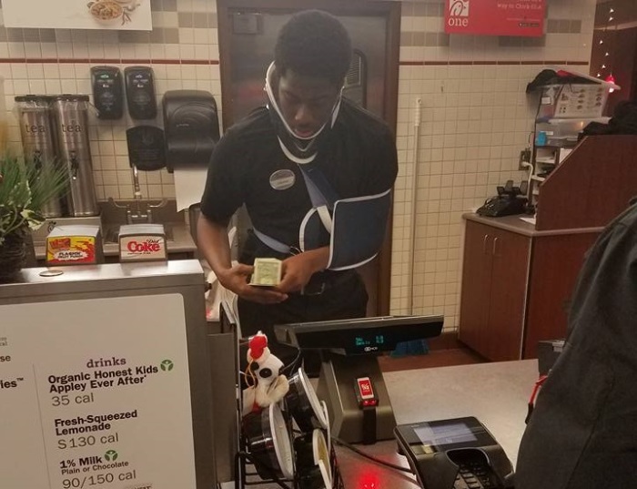 Jakeem Tyler, 18, works in a neck brace and sling at the Chick-fil-A location along Rockville Road in Indianapolis, Indiana.