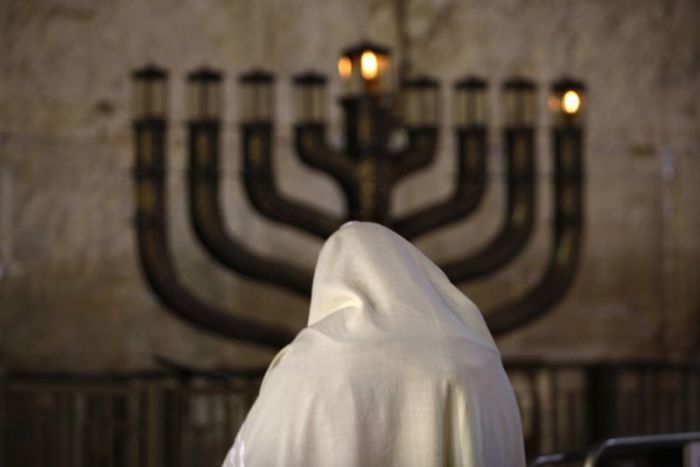 A Jewish man prays in front Menorah candles on the first night of the Jewish festival of Hanukkah at the Western Wall in Jerusalem's Old City December 21, 2008. Hanukkah, which means 'dedication', and is also referred to as 'The Festival of Lights', commemorates the rededication of the Temple in Jerusalem after its desecration by foreign forces. (JERUSALEM)