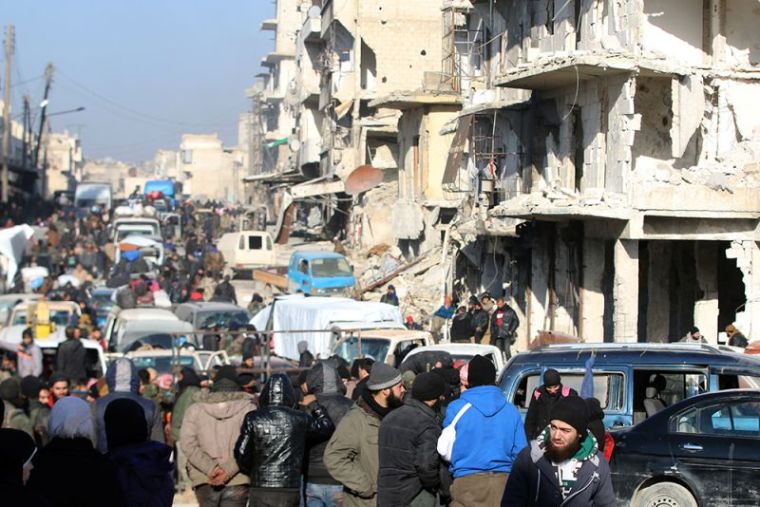 Rebel fighters and civilians wait near damaged buildings to be evacuated from a rebel-held sector of eastern Aleppo, Syria December 18, 2016. Picture taken December 18, 2016.