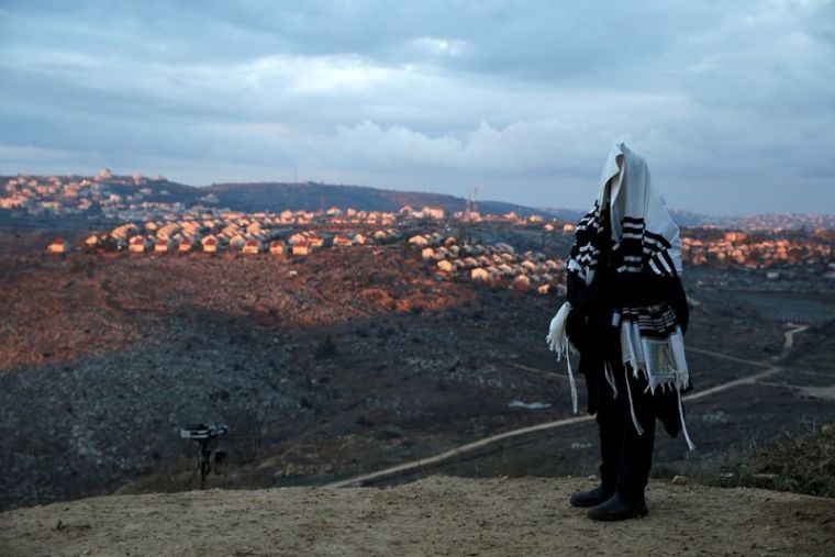 A Jewish man covered in a prayer shawl, prays in the Jewish settler outpost of Amona in the West Bank, December 18, 2016.