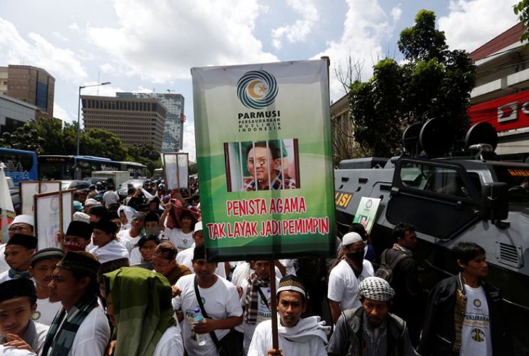 Muslim protesters are seen outside a court at the blasphemy trial of Jakarta's incumbent governor Basuki Tjahaja Purnama, also known as Ahok, in Jakarta, Indonesia, December 20, 2016. The placard shows a picture of the governor and reads 'A blasphemer is unfit to be a leader.'