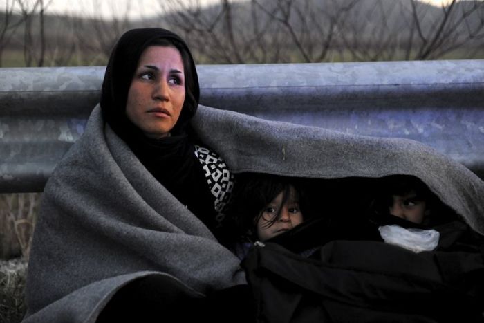 An Afghan mother covers herself and her children with a blanket while trying to reach the Greek-Macedonian border, following reports that Macedonia has closed its borders with Greece to Afghan migrants, near the village of Idomeni, Greece, February 21, 2016.
