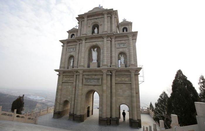 A villager walks through a Catholic church's building to pray on the top of a hill, near a Catholic church on the outskirts of Taiyuan, North China's Shanxi province, December 24, 2016.