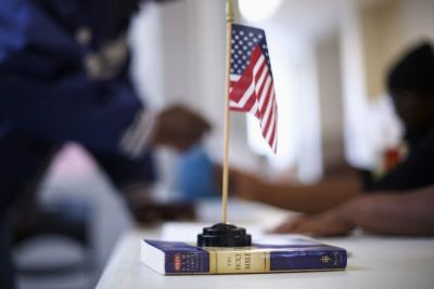 A miniature U.S. flag rests on a copy of the Bible at voter registration at West Philadelphia High School on U.S. midterm election day morning in Philadelphia, Pennsylvania, November 4, 2014.