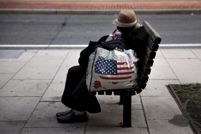 A homeless woman sits on a bench few blocks away from the White House in downtown Washington, September 1, 2015.