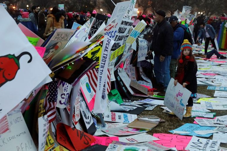 A young girl uses protest signs to build a wall while taking part in the Women's March to protest Donald Trump's inauguration as the 45th president of the United States close to the White House in Washington, January 21, 2017.