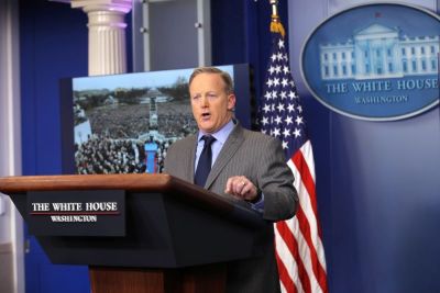 Press Secretary Sean Spicer delivers a statement while a television screen show a picture of U.S. President Donald Trump's inauguration at the press briefing room of the White House in Washington U.S., January 21, 2017.