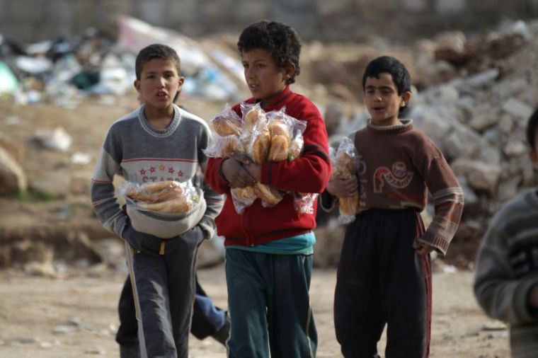 Boys carry sandwiches near rubble of damaged buildings in al-Rai town, northern Aleppo countryside, Syria, January 20, 2017.