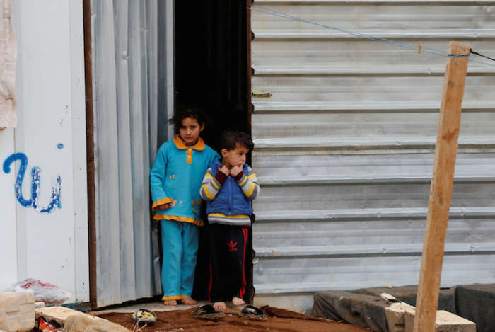 Syrian refugee children stand in front of their family residence during rainy weather at the Al Zaatari refugee camp in the Jordanian city of Mafraq, near the border with Syria December 18, 2016.