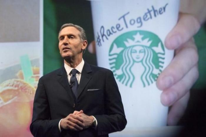 Starbucks Corp Chief Executive Howard Schultz, pictured with images from the company's new ''Race Together'' project behind him, speaks during the company's annual shareholder's meeting in Seattle, Washington March 18, 2015.