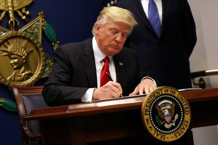 U.S. President Donald Trump signs an executive order to impose tighter vetting of travelers entering the United States, at the Pentagon in Washington, U.S., January 27, 2017. The executive order signed by Trump imposes a four-month travel ban on refugees entering the United States and a 90-day hold on travelers from Syria, Iran and five other Muslim-majority countries. Picture taken January 27, 2017.