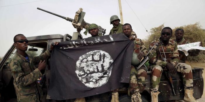 Nigerian soldiers hold up a Boko Haram flag that they had seized in the retaken town of Damasak, Nigeria, March 18, 2015.