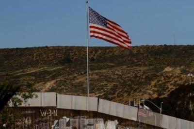 A U.S. flag is seen next to a section of the wall separating Mexico and the United States, in Tijuana, Mexico