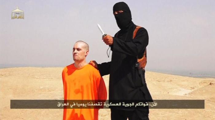 A masked Islamic State militant holding a knife speaks next to man purported to be U.S. journalist James Foley at an unknown location in this still image from an undated video posted on a social media website.