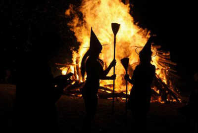 Two women dressed up as witches take pictures in front of the bonfire during the traditional San Juan's (Saint John) night on June 24, 2015.