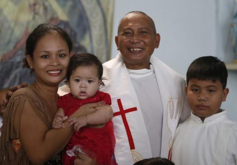Roman Catholic priest Father Elmer Cajilig smiles as he poses with his common law wife Kristine and their children after a holy mass at a chapel in Lambunao, Iloilo on Panay island in central Philippines January 11, 2015.