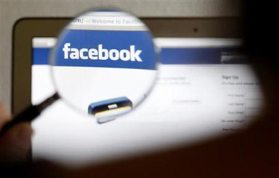 In this photo illustration, a Facebook logo on a computer screen is seen through a magnifying glass held by a woman in Bern May 19, 2012.