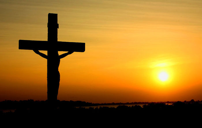 A silhouette of the image of the crucified Christ against a sunset.