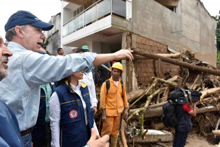 Colombia's President Juan Manuel Santos (L) gestures while visiting a flooded area after heavy rains caused several rivers to overflow, pushing sediment and rocks into buildings and roads in Mocoa, Colombia, April 1, 2017.