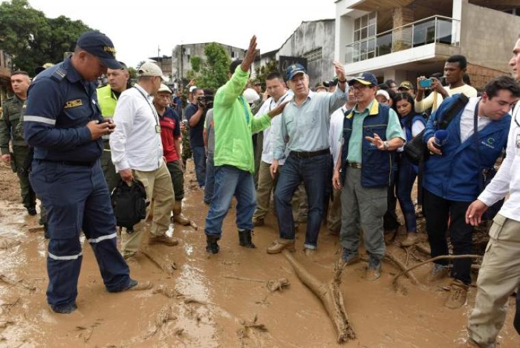 Colombia's President Juan Manuel Santos (4th R) gestures while visiting a flooded area after heavy rains caused several rivers to overflow, pushing sediment and rocks into buildings and roads in Mocoa, Colombia, April 1, 2017.