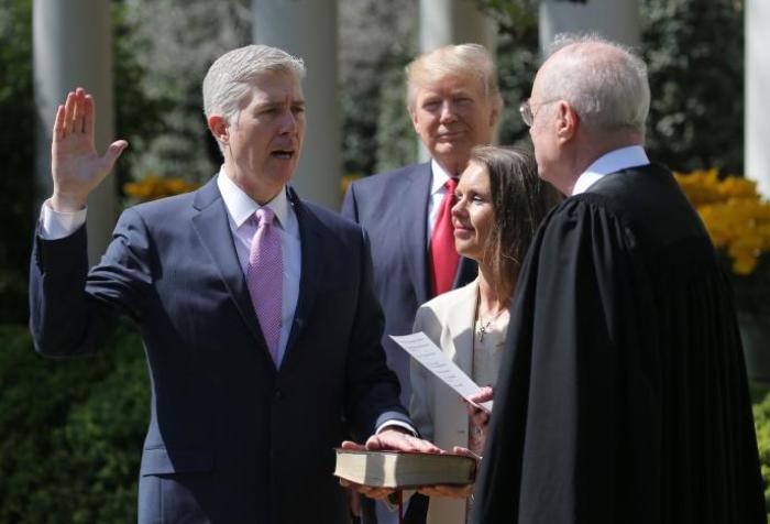 Judge Neil Gorsuch (L) is sworn in as an associate justice of the Supreme Court by Supreme Court Associate Justice Anthony Kennedy (R) , as U.S. President Donald J. Trump (C) watches with Louise Gorsuch in the Rose Garden of the White House in Washington, U.S., April 10, 2017.