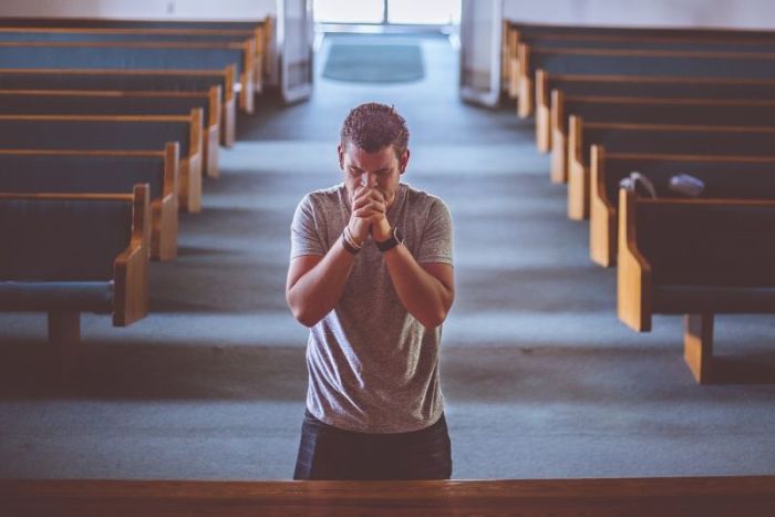 A man on his knees praying inside a church