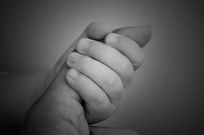 Credit : A mother holds the hand of her newborn child.