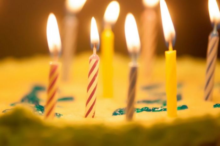 A cake with numerous candles is served during a birthday.