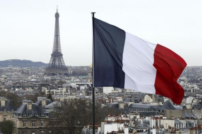 A city view shows the French flag above the skyline of the French capital as the Eiffel Tower and roof tops are seen in Paris, France, March 30, 2016.