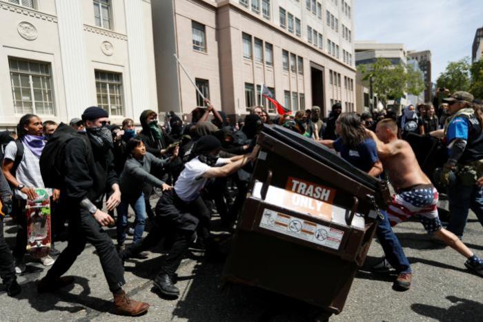 Demonstrators for (R) and against (L) U.S. President Donald Trump push a garbage container toward each other during a rally in Berkeley, California in Berkeley, California, U.S., April 15, 2017.