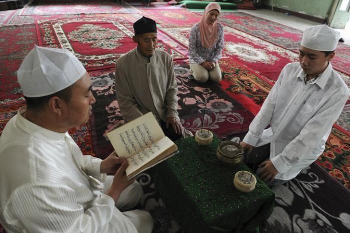 A Muslim man from the northwestern region of Xinjiang Uyghur Autonomous Regions reads Quran while others sit and listen.