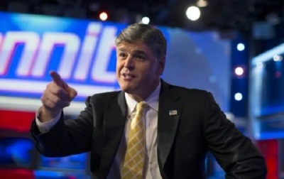 Sean Hannity posing for a photograph as he sits on his show's set