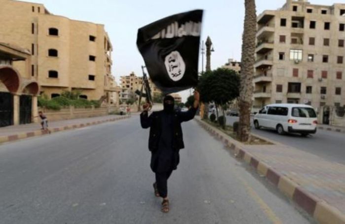 A member loyal to the Islamic State in Iraq and the Levant waves an ISIS flag in Raqqa, Syria, June 2014.