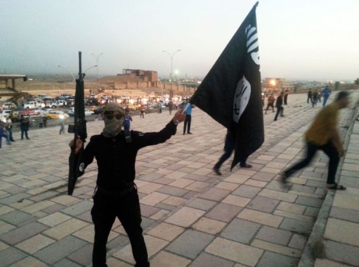 An ISIS fighter waves the terrorist group's flag in Mosul, Iraq on June 23, 2014.